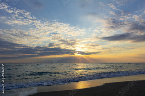 Rays of light through the clouds for a magical sunrise over the calm sea