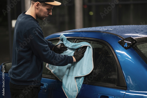 professional detailer wiping car surface with a microfiber rag in workshop