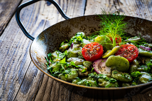 Canvas-taulu Broad beans with cherry tomatoes, garlic, toasted bread and parsley in cooking p