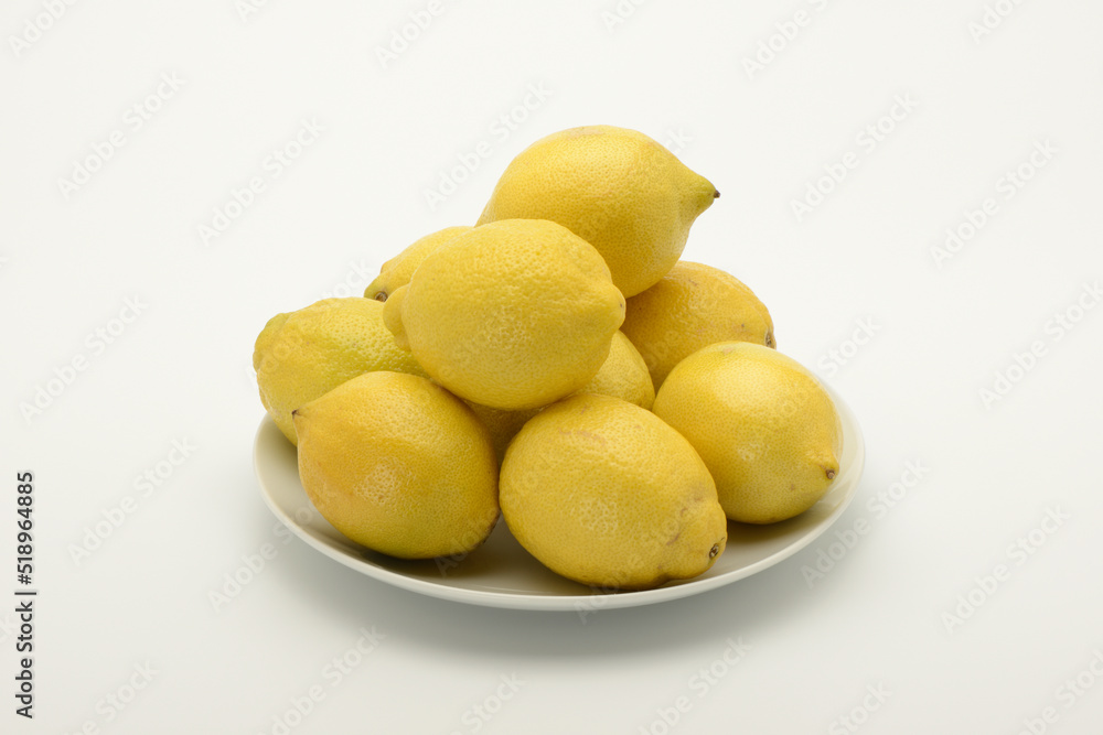 Varios limones en un plato sobre fondo blanco Varios limones en un plato sobre fondo blanco