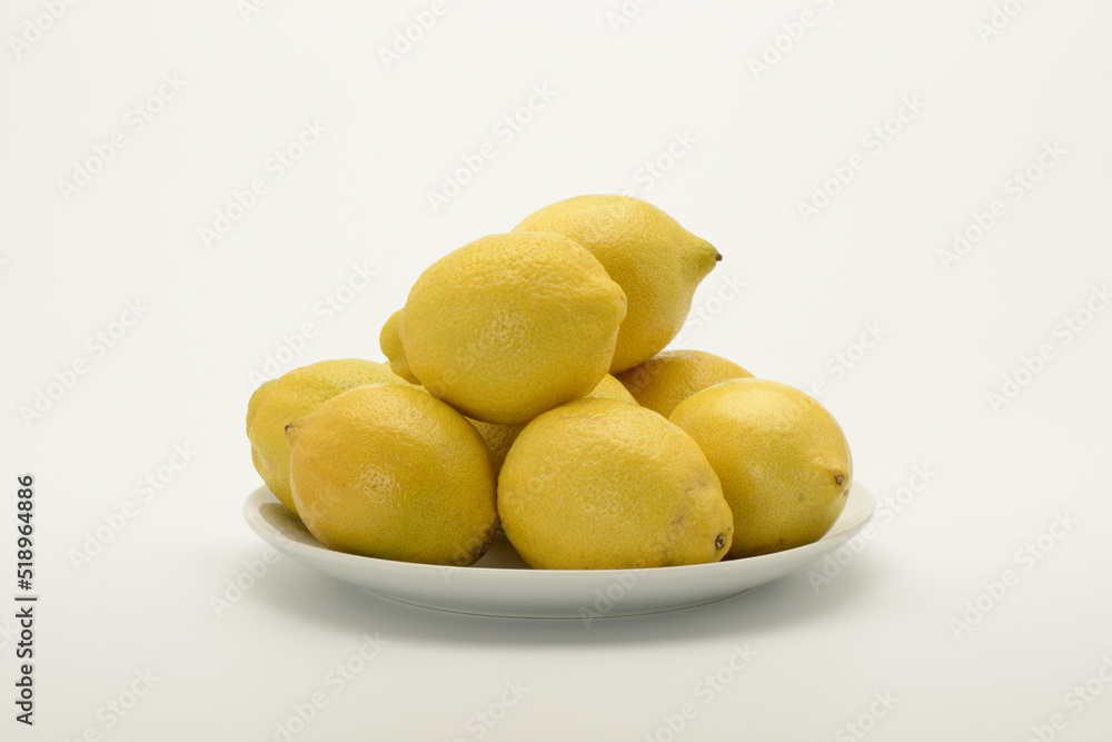 Varios limones en un plato sobre fondo blanco