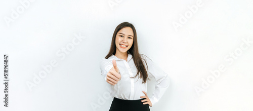 wide banner. asian pretty business woman smiling and showing thumbs up on copy space area on panoramic white background, business finance, online marketing, entertainment, internet technology concept © Vittaya_25