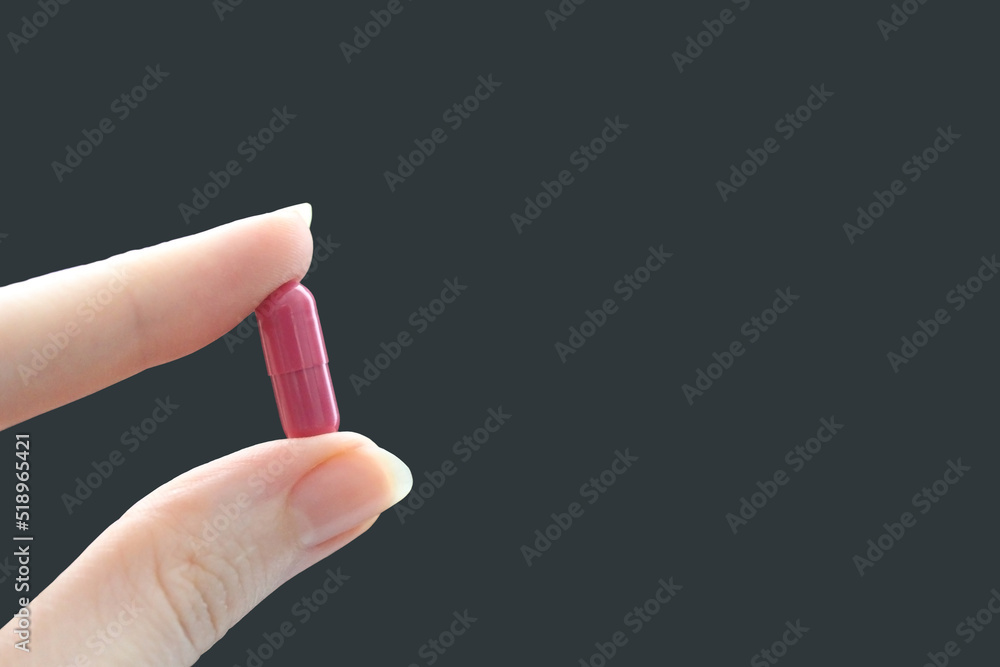 Raspberry capsule in hand on a dark background. Raspberry capsule in hand on a dark background.