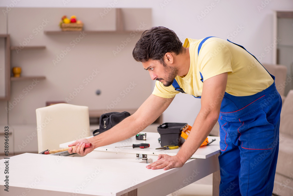 Fototapeta premium Young male carpenter repairing table at home