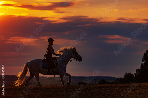 young woman galloping on horseback during sunset © michal