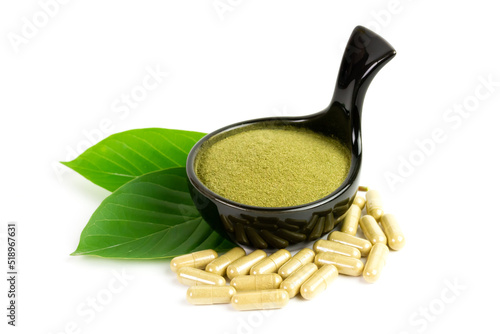 Mitragyna Speciosa Korth or kratom capsules on black bowl with green leaf isolated on white background. 