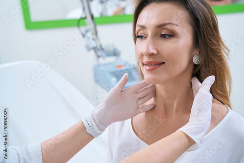 Dermatologist with gloved hands touches the patient neck