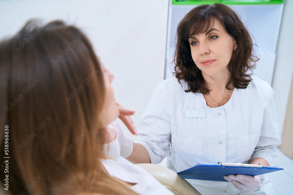 Dermatologist talking to a patient sitting in a chair Dermatologist talking to a patient sitting in a chair