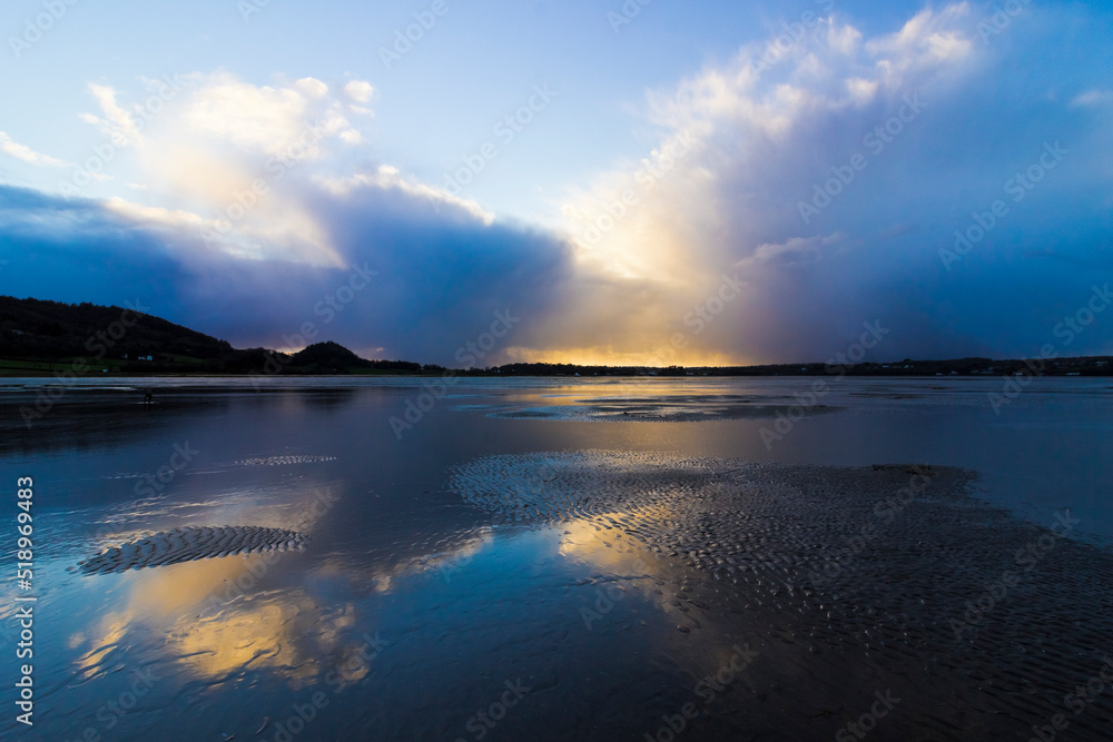 Reflection on the beach surface of a storm cloud system moving away from Red Wharf Bay, Gwynedd, Anglesey, North Wales