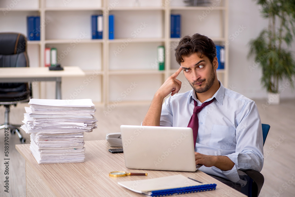 Young male employee and too much work in the office Young male employee and too much work in the office
