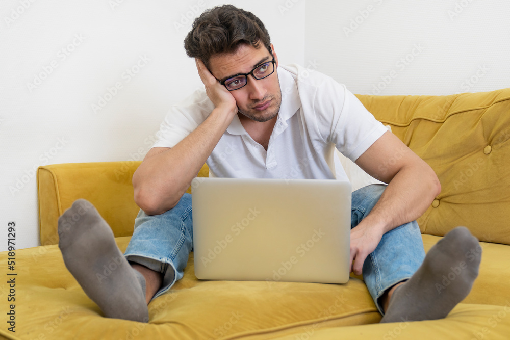 Upset and tired student sitting on the couch and studying online at home. Distance learning concept Upset and tired student sitting on the couch and studying online at home. Distance learning concept