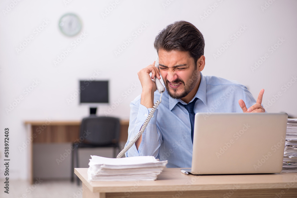 Young male employee and too much work in the office Young male employee and too much work in the office