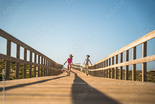 Overjoyed female kids having fun while running through the huge bridge at the morning