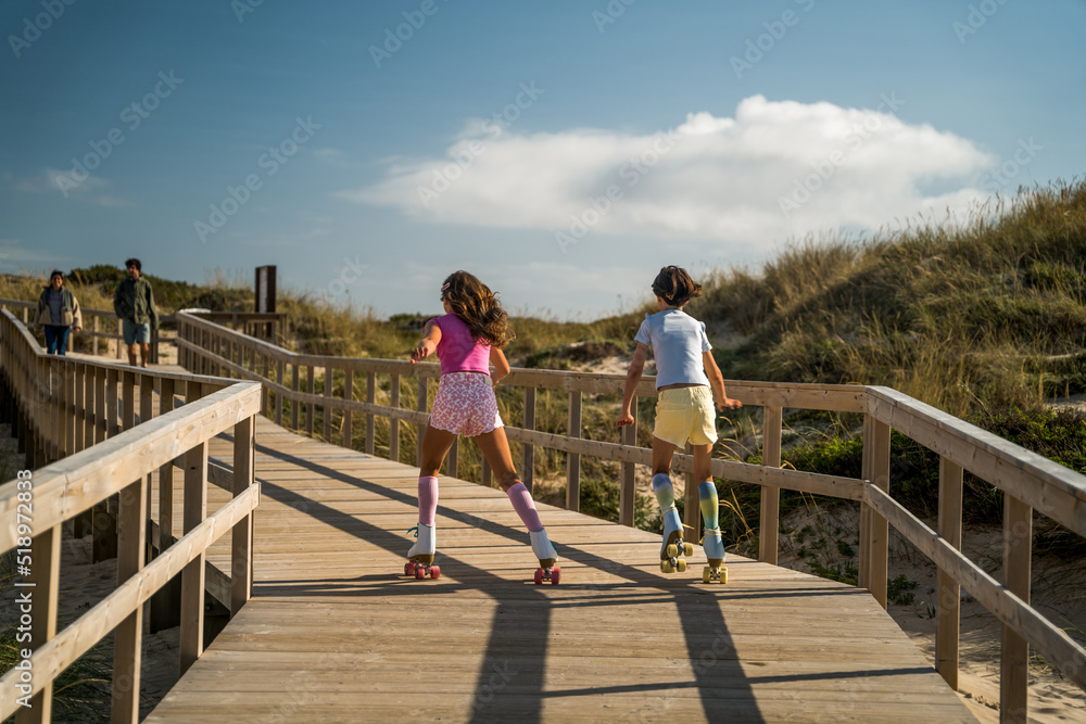 Child girls riding at the roller skates through the bridge around the nature