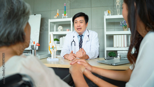 Daughter took an elderly woman patient to the doctor to follow up with knee treatment at the hospital. Male doctor giving advice and tell the patient about the precautions in knee treatment.