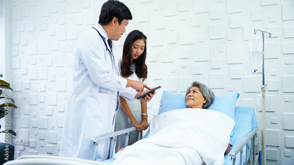 Expert male doctor came in to inquire about the symptoms of an elderly female patient who was lying on the patient's bed. Elderly female patient and her daughter chatting with a male doctor. Expert male doctor came in to inquire about the symptoms of an elderly female patient who was lying on the patient's bed. Elderly female patient and her daughter chatting with a male doctor.