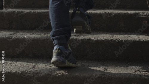 Back view of boy walking on stairs outdoors building background. A boy with a backpack behind him, school, climbs the stairs to the top