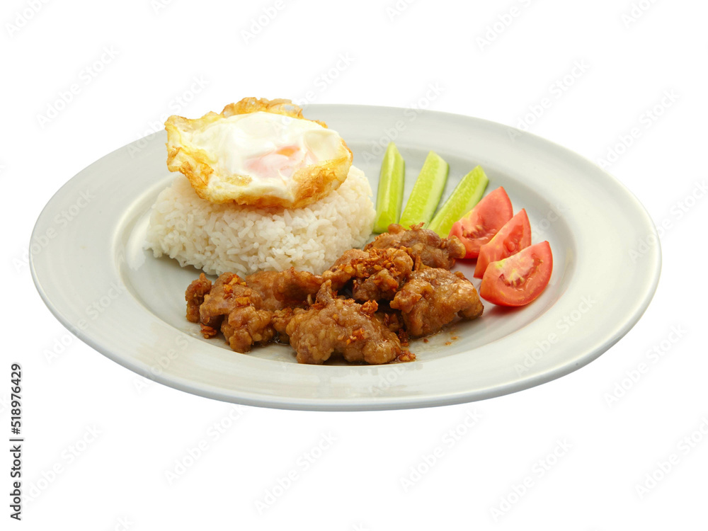 Thai Food Stir-Fried Pork with Garlic and Thai Peppers ontop Fried Crispy Garlic served with Rice ,Fried egg and tomato cucumber carved white plate side view isolated on background Thai Food Stir-Fried Pork with Garlic and Thai Peppers ontop Fried Crispy Garlic served with Rice ,Fried egg and tomato cucumber carved white plate side view isolated on background