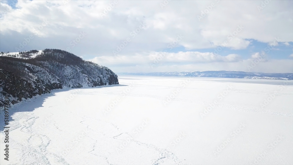 Baikal Lake in winter season, aerial view. Clip. Flying over the rocks and hills near the shore of the frozen amazing water reservoir, the beauty of nature concept.