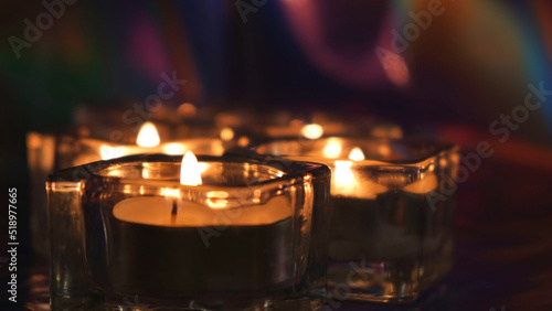 Burning candles on table in the darkness. Concept. Close up of small candles in glass candlesticks standing on the table in dark room creating romantic atmosphere for date.