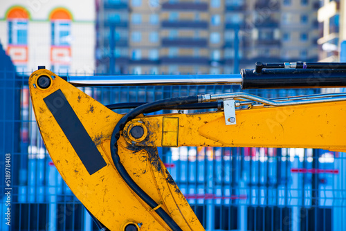 part of the excavator boom on the background of a multi-storey building in a blur
