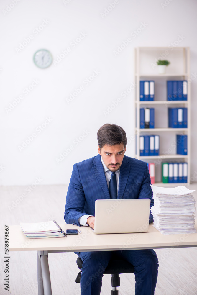 Young male employee and too much work in the office Young male employee and too much work in the office