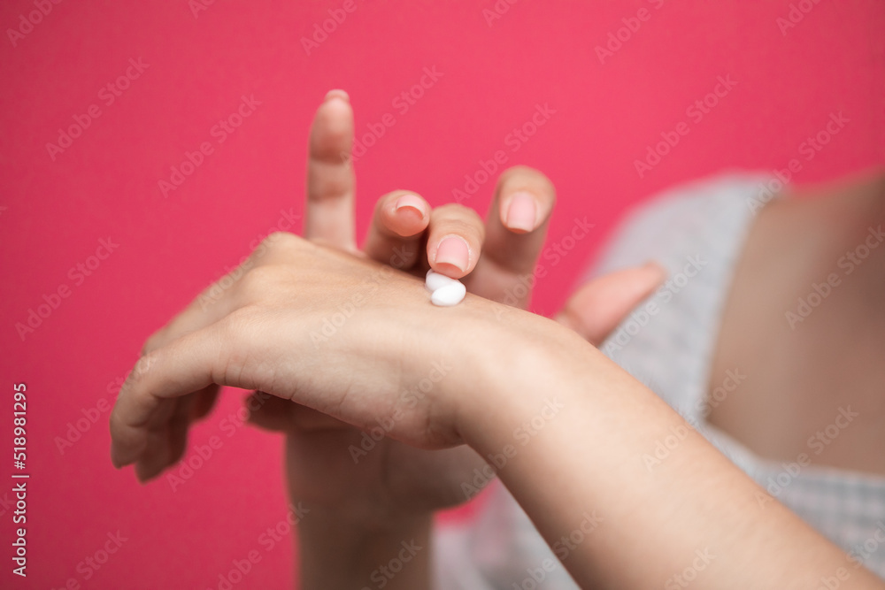 Naklejka premium Woman applies cream on her hands isolated on pink background