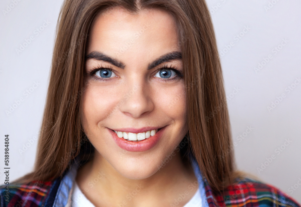 Studio portrait of happy young woman in plaid shirt posing against wall. Studio portrait of happy young woman in plaid shirt posing against wall.