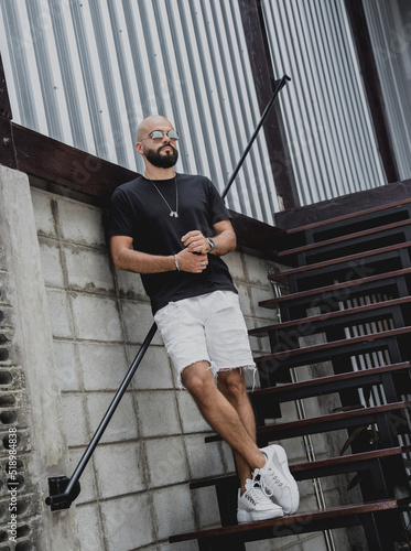 A young man in t-shirt and shorts on the stairs at city streets