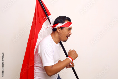 Foto Asian man with running gesture while holding indonesian flag