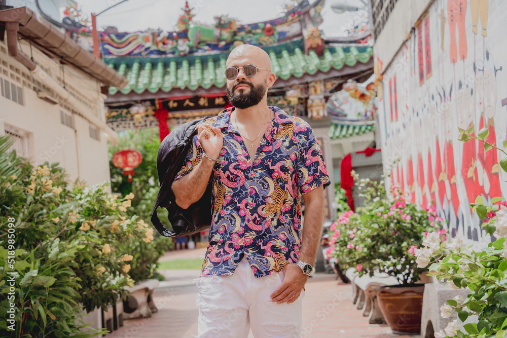 Fototapeta premium Young man with a backpack on the background of an asian temple