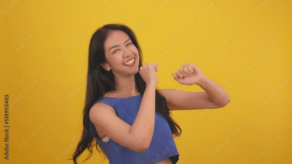 Happy attractive asian young woman dancing isolated on yellow background.Cheerful pretty girl wear casual dress dancing raising hands smiling and moving body follow music with positive. Happy attractive asian young woman dancing isolated on yellow background.Cheerful pretty girl wear casual dress dancing raising hands smiling and moving body follow music with positive.
