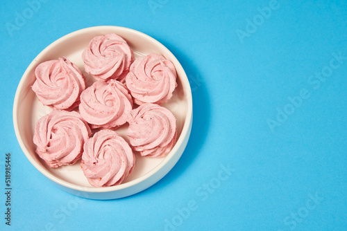 beautiful pink homemade marshmallow in a white round plate on a blue background