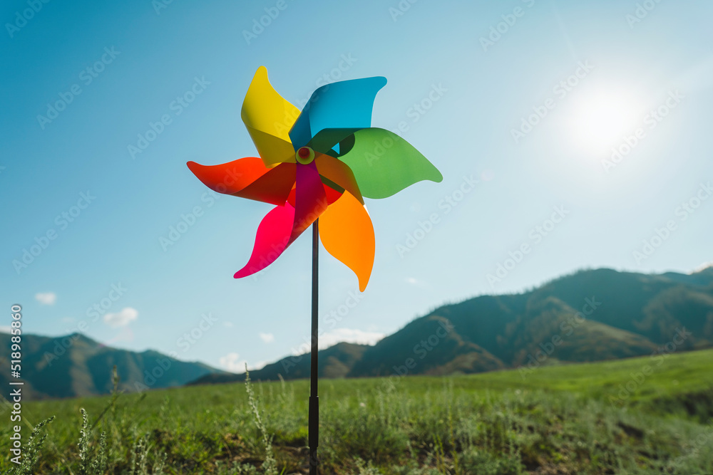 Windmill against, pinwheel the backdrop of green mountains and sky Windmill against, pinwheel the backdrop of green mountains and sky