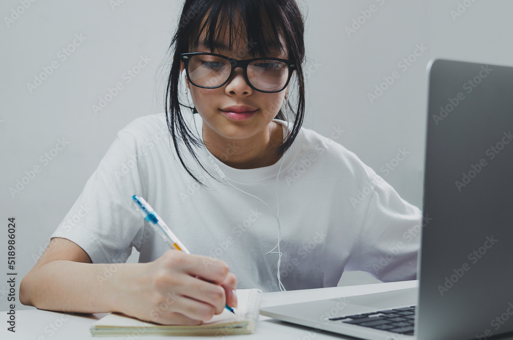 girl holding pen writing book study learning digital internet video online computer laptop at home. girl holding pen writing book study learning digital internet video online computer laptop at home.