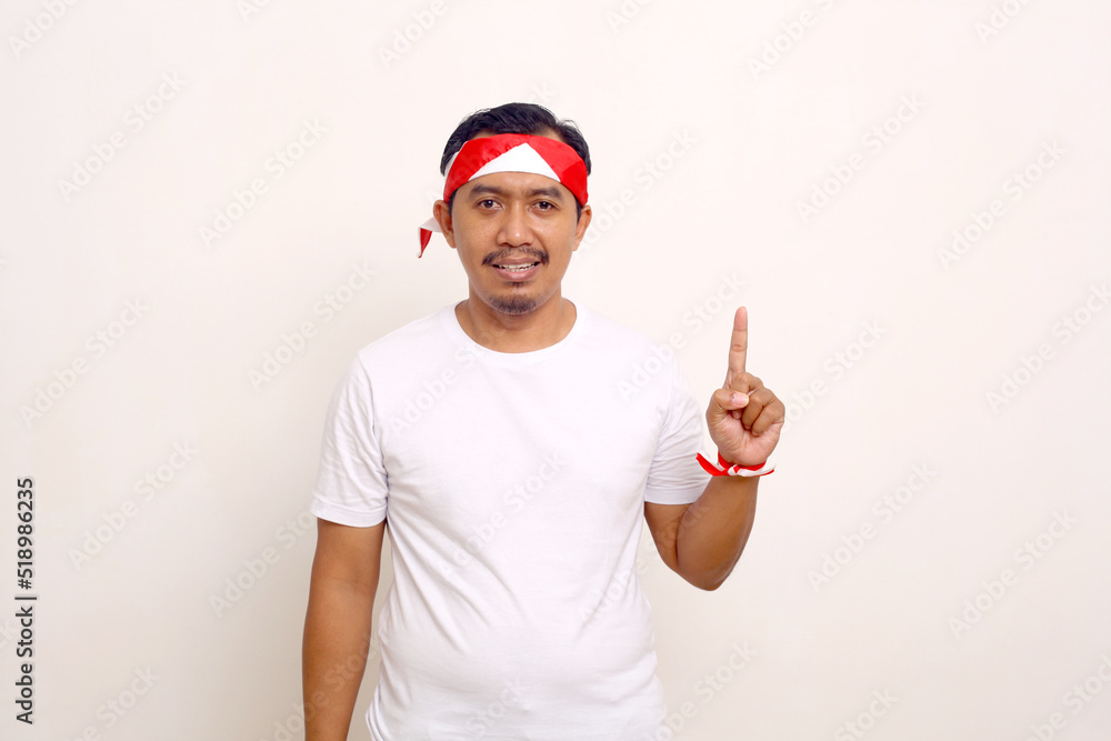 Naklejka premium Indonesian man standing while showing one finger. Independence day gesture. Isolated on white