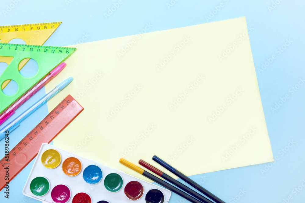 Naklejka premium empty yellow sheet for text surrounded by school stationery accessories - watercolor, pencils, ruler, pens, triangle with copy space