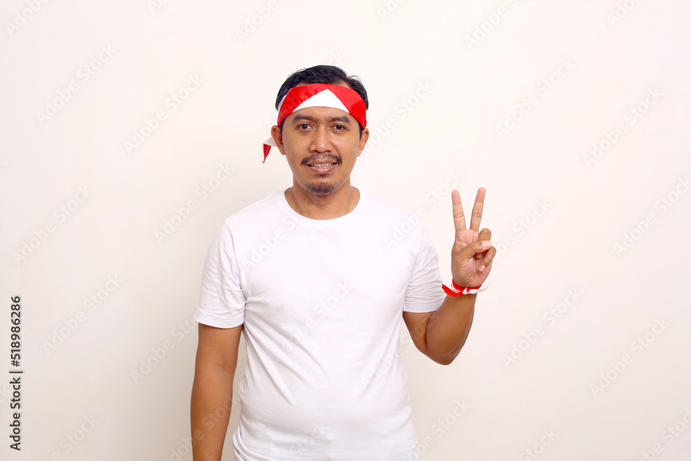 Indonesian man standing while showing two fingers. Independence day gesture. Isolated on white Indonesian man standing while showing two fingers. Independence day gesture. Isolated on white