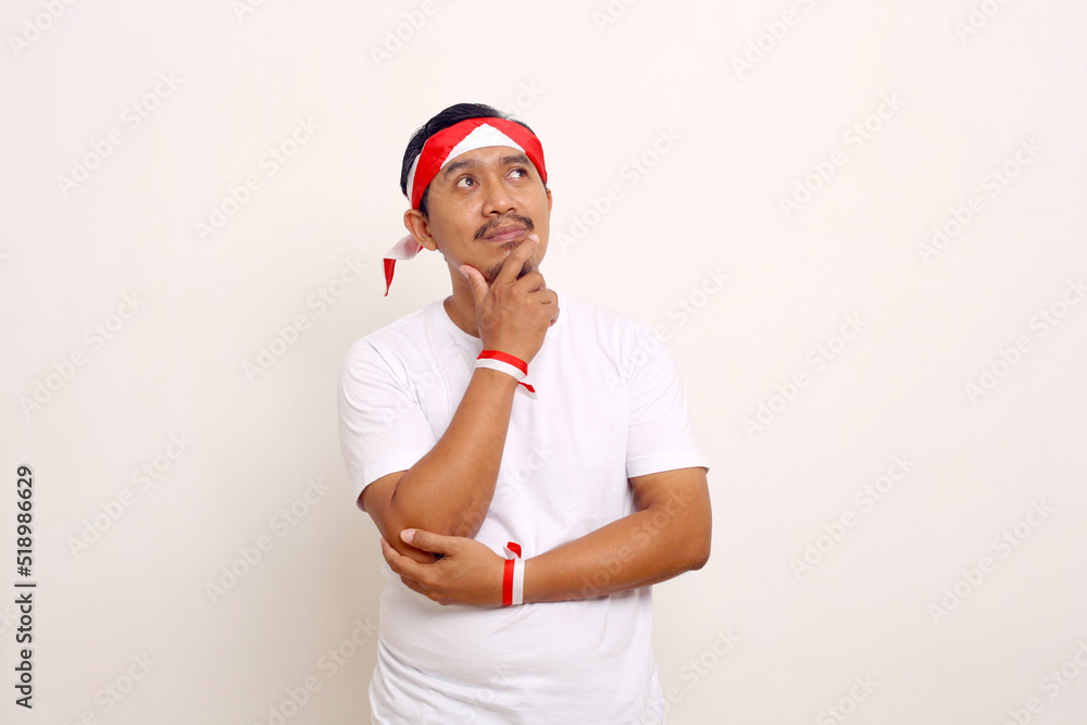 Happy asian man standing while thinking some idea. Indonesian independence day concept Happy asian man standing while thinking some idea. Indonesian independence day concept
