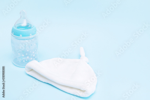 bottle with a pacifier and a cap for a baby on a blue background with copy space