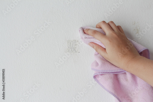 woman cleaning and remove sticky rough glue and tape remain on the old concrete wall.