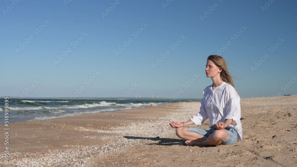 Girl meditating by the sea. Wind shakes long blond hair Girl meditating by the sea. Wind shakes long blond hair
