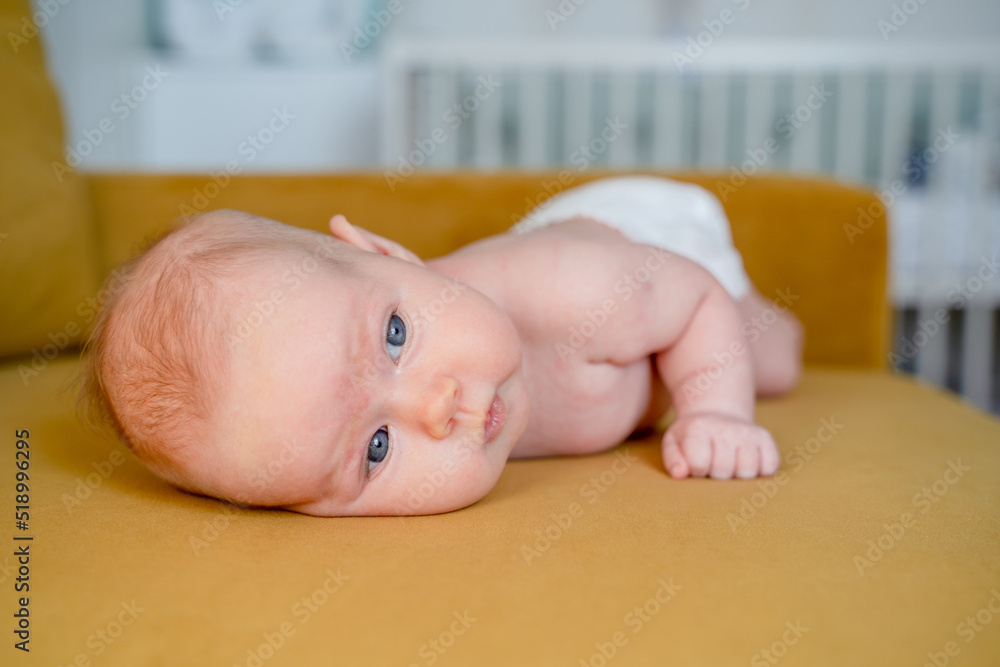 Foto de Cute baby learns to raise his head lying on his stomach on a