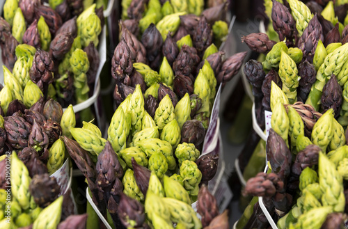 bundles of green and purple asparagus on a market