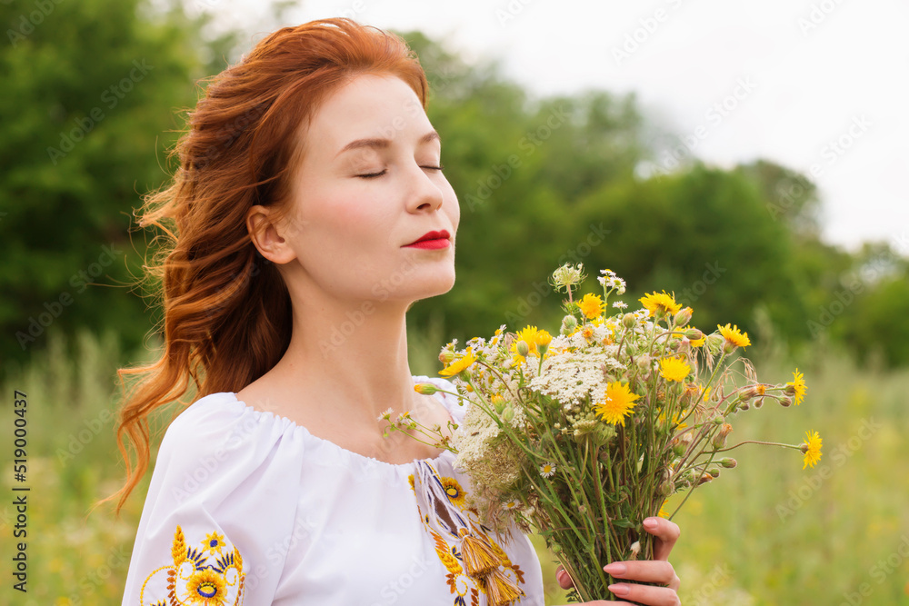 The Ukrainian woman enjoys freedom with a bouquet of wild flowers The Ukrainian woman enjoys freedom with a bouquet of wild flowers