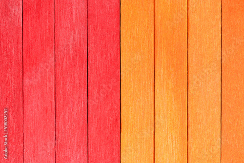 Vivid background from orange and red wooden planks. Autumnal Wooden textured background in two colours. Red and orange painted wooden boards arranged vertically in a row.