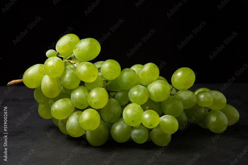 White grapes on a black background. Grape sort. Delicious and healthy fruit White grapes on a black background. Grape sort. Delicious and healthy fruit