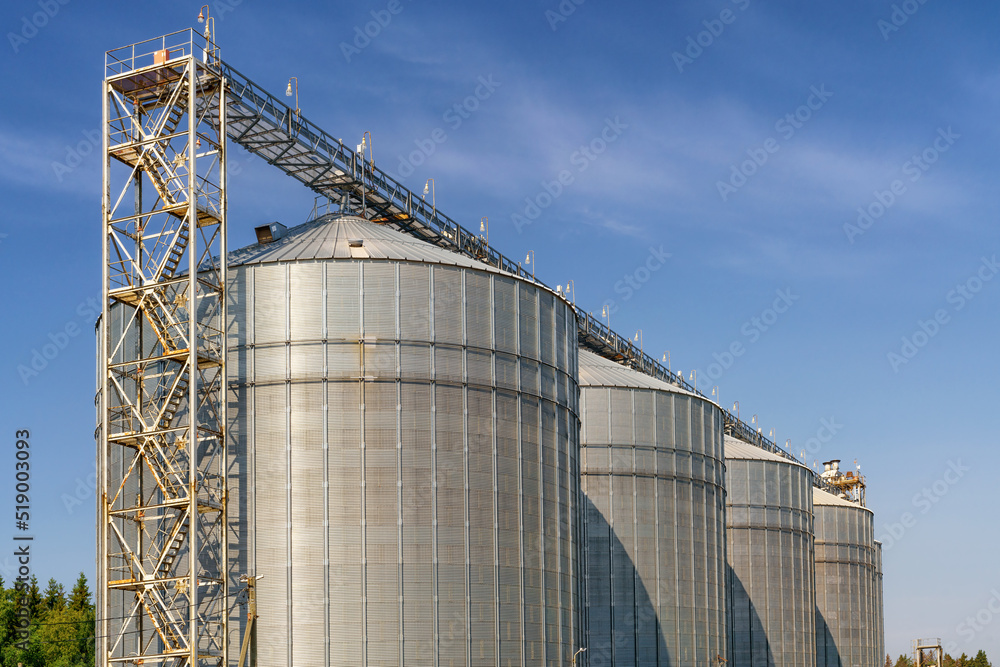 Large metal elevator tanks against a bright blue sky