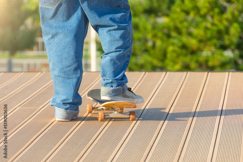 Guy in blue jeans and sneakers stands on the floor with a skateboard putting his foot on it. Guy in blue jeans and sneakers stands on the floor with a skateboard putting his foot on it.