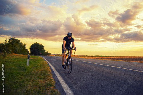 Young sports man cycling with bicycle on the road in summer © Solid photos